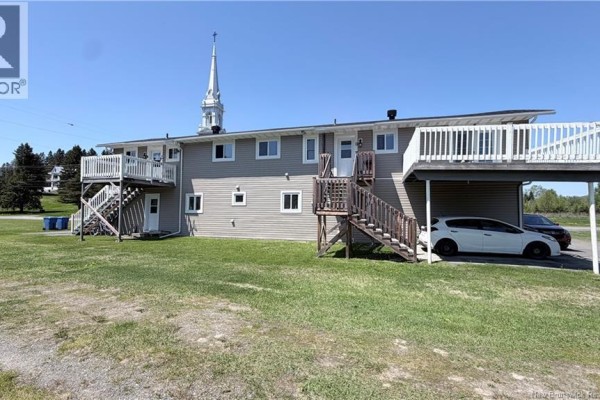 Rear exterior of a two-story multi-family building with grey siding, outdoor staircases, and covered parking. - 3766 Principal Street, Baker Brook