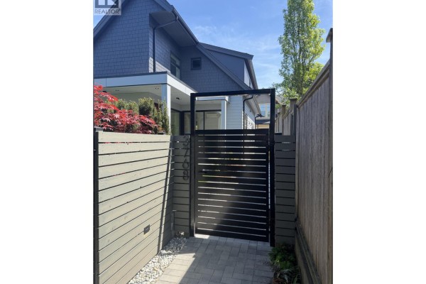 Covered patio entrance with sliding glass doors and a paved walkway. - 3768 Fleming Street, Vancouver