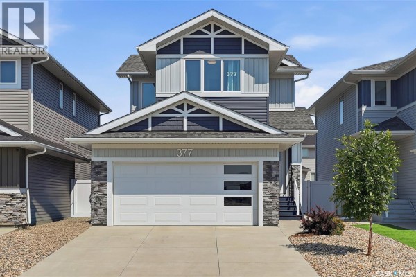 Front exterior of a two-story house with a double garage and modern gray siding. - 377 Germain Manor, Saskatoon