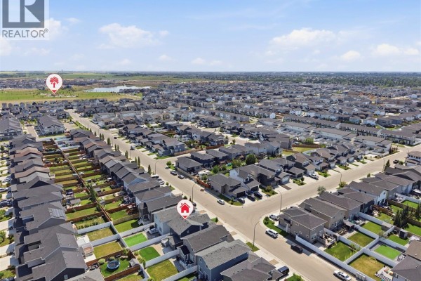 Aerial view of a suburban neighborhood with rows of modern houses under a blue sky. - 377 Germain Manor, Saskatoon