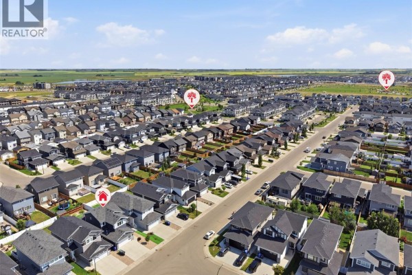 Aerial view of a suburban neighborhood with rows of modern houses under a blue sky. - 377 Germain Manor, Saskatoon