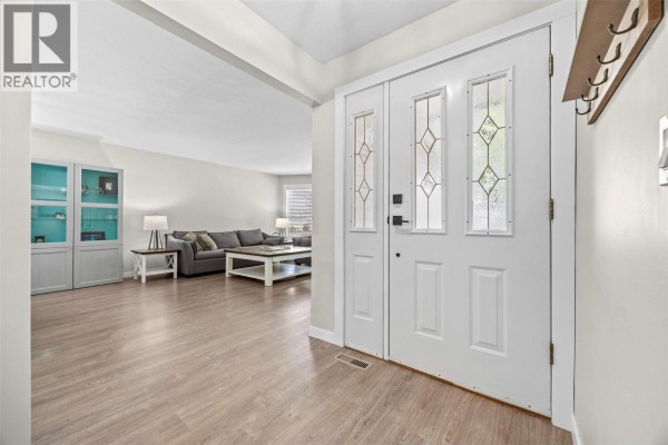 Interior foyer with white double doors, light wood laminate flooring, and view into living room. - 377 Sumac Road E, Kelowna