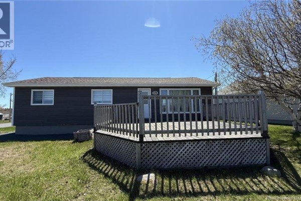 White detached garage with a white roll-up door and a light blue side door. - 378 Rue De L'ile, Caraquet
