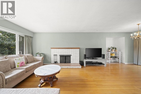 Spacious living room with hardwood floors, a fireplace, and large windows. - 3783 Price Street, Burnaby