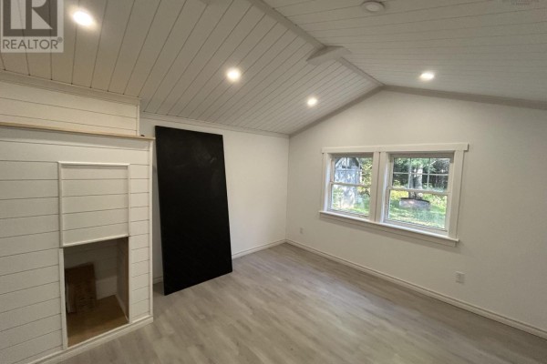 Interior room with white plank vaulted ceiling, gray laminate flooring, and two windows overlooking trees. - 3786 Prospect Road, Casey Corner
