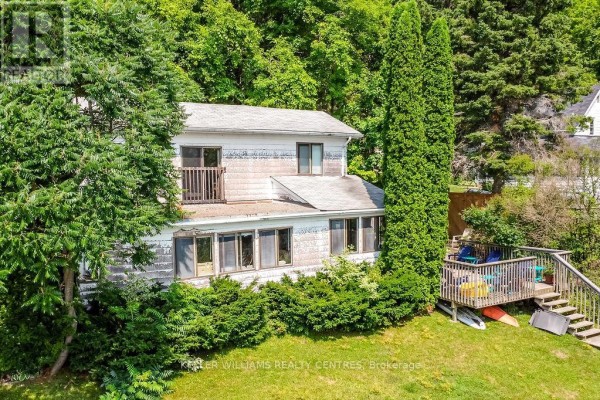 Close-up of the house with a balcony, surrounded by trees and greenery. - 379 Champlain Road, Penetanguishene