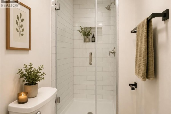 Bathroom with white subway tile shower, glass door, toilet, and black towel rack. - 379 Main Street Unit# 3, Woodstock