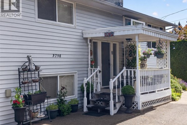 Close-up of the covered front porch entrance with white railings, stairs, and potted plants. - 3798 Laurel Dr, Royston