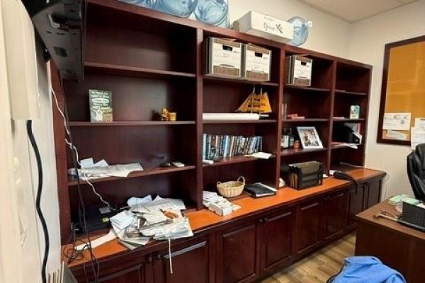 Wooden built-in bookshelves with doors and an orange countertop against a light brown wall. - 3799 Main Street, Belledune