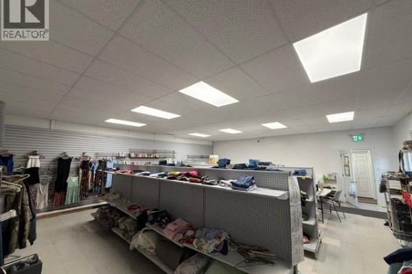 Retail space with clothing racks and shelves of folded items under bright fluorescent lights. - 3799 Main Street, Belledune