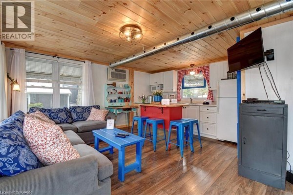 Open-concept living area and kitchenette with a grey sectional and blue accents. - 37b Cedar Drive, Turkey Point