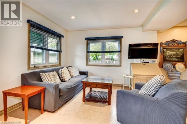 Cozy seating area with a navy blue sectional sofa and rustic wood walls. - 37c Cedar Drive, Turkey Point