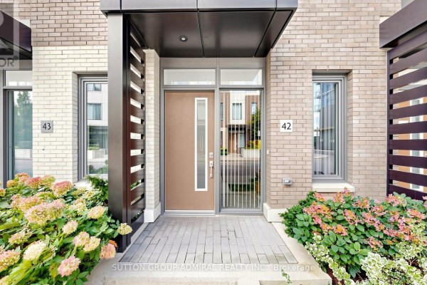 Close-up of townhouse entrance with a brown door, grey metal gate, and landscaping. - Th 42 - 1020 Portage Parkway, Vaughan