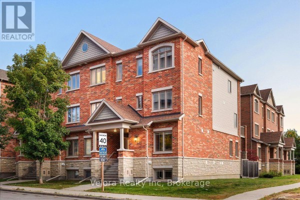 Side view of a red brick townhouse complex with a tree in the foreground. - 494 Leboutillier Avenue, Ottawa