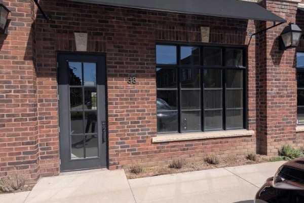Brick building facade with black awning, glass door, and large multi-paned window. - 38 - 74 Jutland Road, Toronto