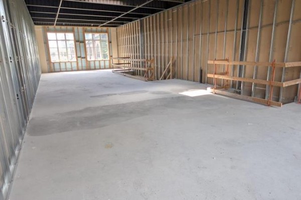 Interior unfinished commercial space with concrete floor, metal stud walls, and wooden railing. - 38 - 74 Jutland Road, Toronto