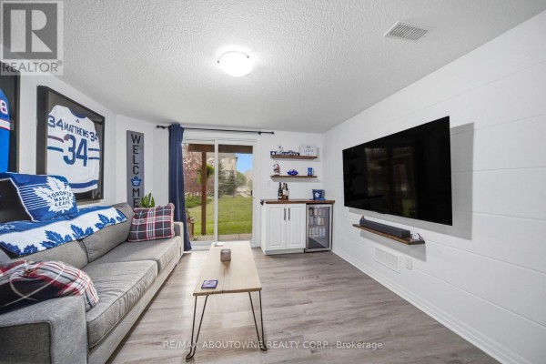 Living room featuring a grey sofa, coffee table, wet bar with a mini-fridge, and a wall-mounted television. - 38 - 750 Lawrence Street, Cambridge