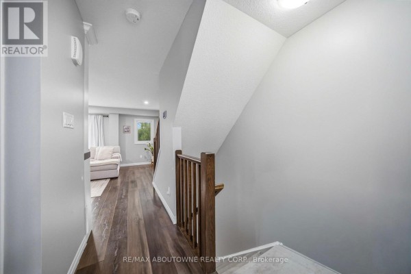 Hallway with grey walls, wood-look flooring, and a wooden staircase railing. - 38 - 750 Lawrence Street, Cambridge