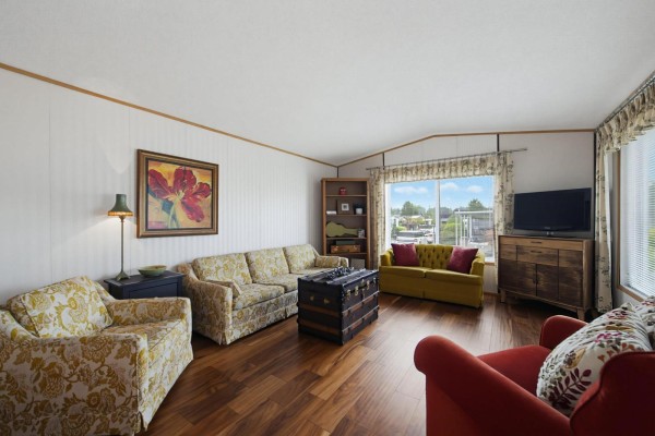 Living room with patterned armchairs, a floral sofa, a yellow tufted sofa, and wood floors. - 38 15875 20 Avenue, Surrey