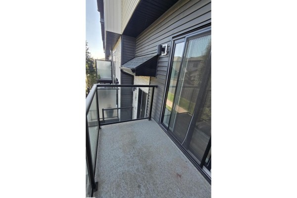 Concrete balcony with glass railings and sliding glass doors leading into the home. - #38 1729 Keene Cr Sw Sw, Edmonton
