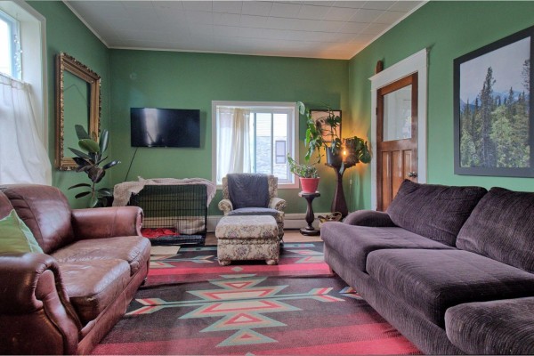 Living room with green walls, brown sofas, a leather chair, and patterned rug. - 38-40 Rue Broad, Gatineau