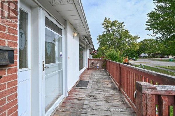 View of the wooden porch and front entrance of the house with a street view in the background. - 38 Algonquin Boulevard, Brampton