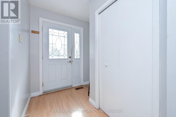 Interior view of a home entrance with a white door, light wood floor, and a large white closet. - 38 Algonquin Boulevard, Brampton