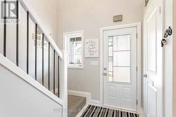 Interior view of a bright entryway with a white staircase, a glass-paneled front door, and light gray walls. - 38 Amber Street, Norfolk