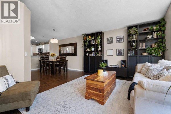 Living room with vaulted ceiling, sofa, armchair, floor lamp, and large windows overlooking the backyard. - 38 Auburn Bay Gardens Se, Calgary