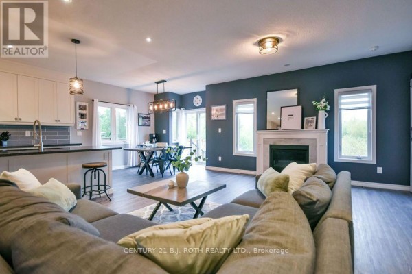 Open concept living, dining, and kitchen area with a gas fireplace and island. - 38 Beverly Street, Springwater