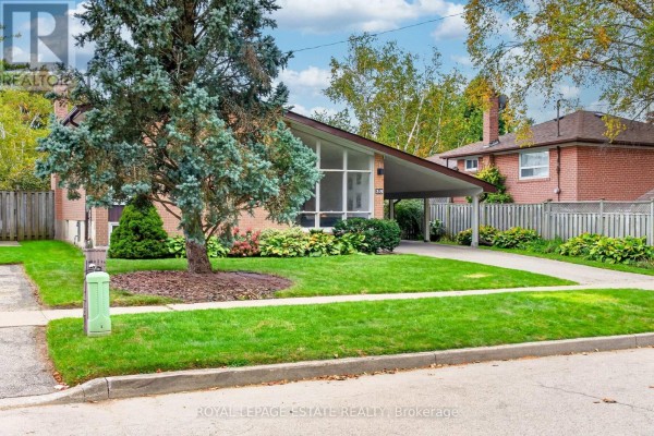 Front view of the house with a large tree in the foreground and a driveway. - 38 Brightside Drive, Toronto