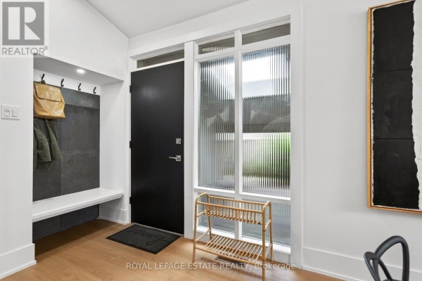 Entranceway with black door, ribbed glass window, coat rack, and bench. - 38 Brightside Drive, Toronto
