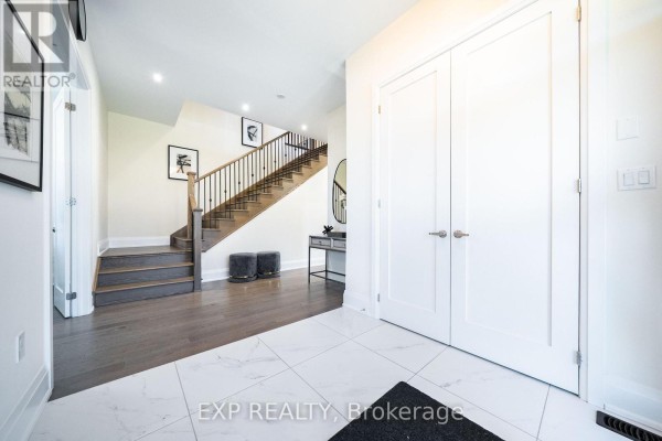 Foyer with dark wood floors, a staircase with a metal railing, and double white doors. - 38 Bud Leggett Crescent, Georgina