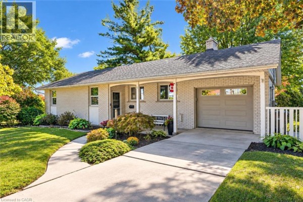 Exterior of a light brick bungalow with a covered porch, garage, and manicured lawn. - 38 Callander Drive, Guelph