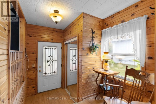 Interior entryway with wood paneled walls, mirrored closet doors, and a rocking chair. - 38 Cameron Drive, Oro Medonte