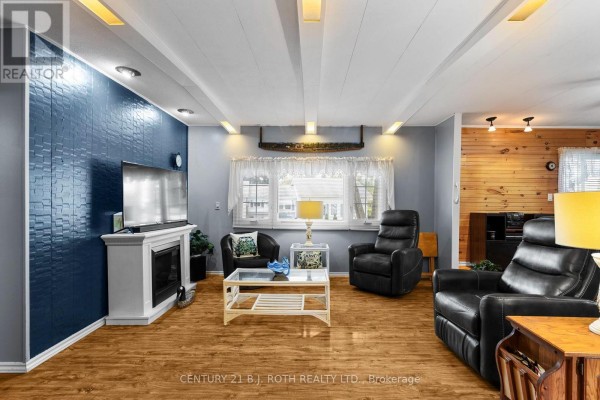 Living room with a gas fireplace, navy textured accent wall, and leather seating. - 38 Cameron Drive, Oro Medonte
