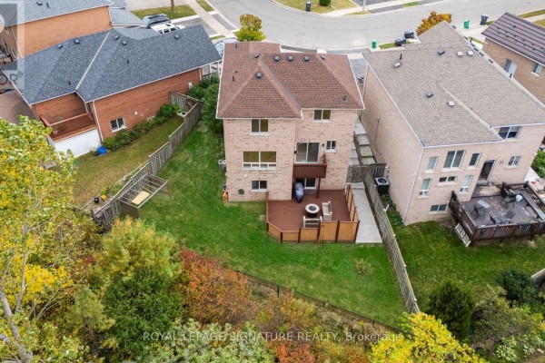 Aerial view of the backyard, featuring a wooden deck, green lawn, and surrounding fences. - 38 Charleswood Circle, Brampton
