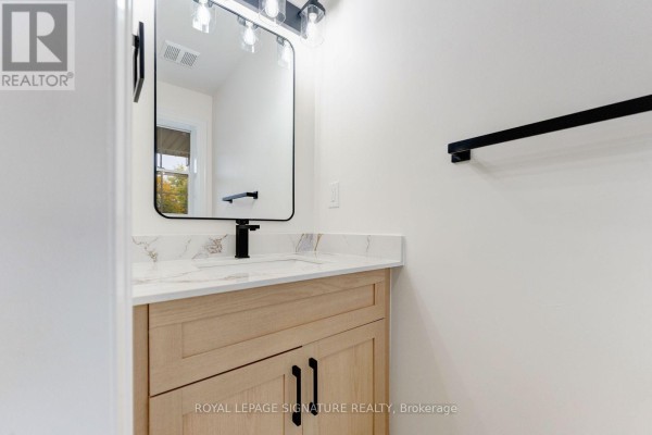 Modern bathroom vanity with a light wood cabinet, white quartz countertop, and a black faucet. - 38 Charleswood Circle, Brampton