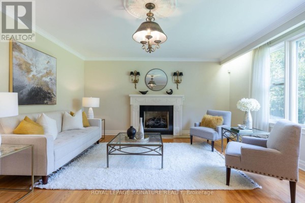 Living room featuring a white fireplace, a sofa, two chairs, a large rug, and hardwood floors. - 38 Danville Drive, Toronto