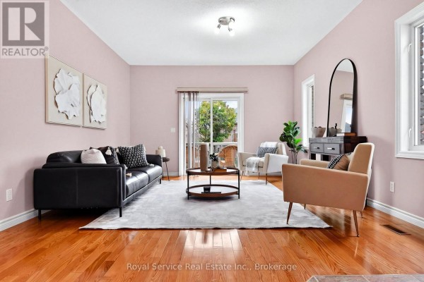 Living room with light pink walls, a black sofa, and hardwood floors. - 38 Finch Drive, Belleville