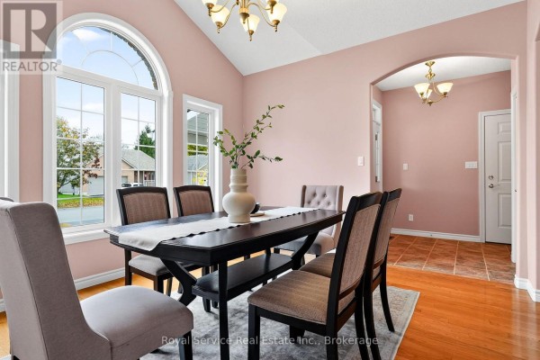 Dining room with a dark wood table, upholstered chairs, and a large arched window. - 38 Finch Drive, Belleville