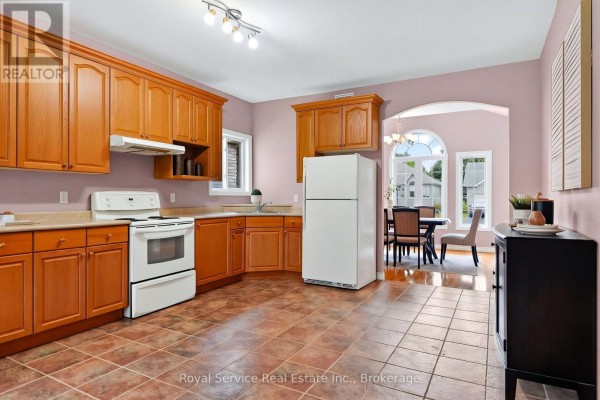 Kitchen with oak cabinets, white appliances, and tile flooring. - 38 Finch Drive, Belleville
