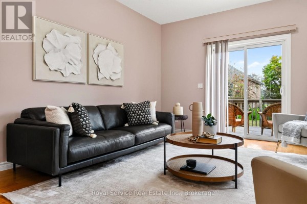 Living room featuring a black leather sofa, a large rug, and sliding glass doors to the patio. - 38 Finch Drive, Belleville