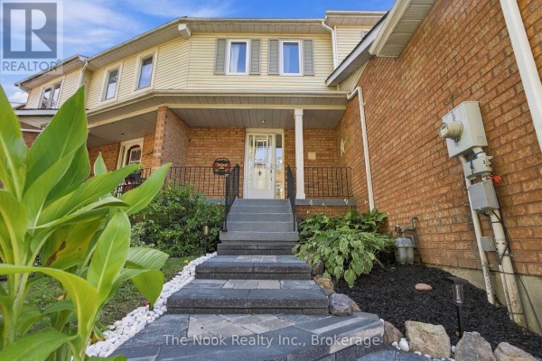 Pathway leading up to the entrance of a townhouse with brick and vinyl siding. - 38 Galbraith Court, Clarington