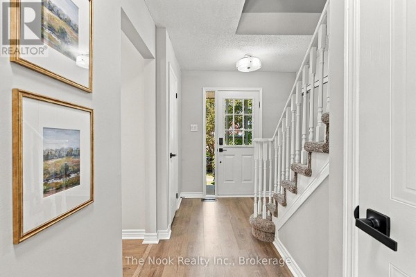Interior entryway of a townhouse with light grey walls, wood flooring, and a staircase. - 38 Galbraith Court, Clarington