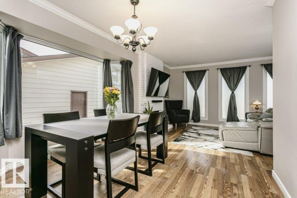 Dining area with a black table and chairs, adjacent to a living room area. - 38 Galen Cr, Sherwood Park