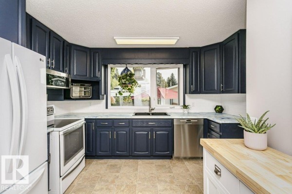 Kitchen with navy blue cabinets, white countertops, stainless steel appliances, and a window. - 38 Galen Cr, Sherwood Park