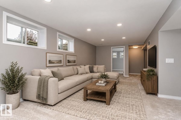 Finished basement living area with a large sectional sofa, coffee table, and wall-mounted TV. - 38 Galen Cr, Sherwood Park