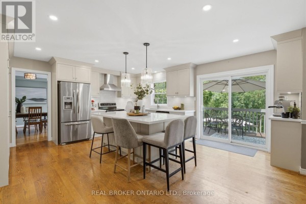 Modern kitchen with a large island, stainless steel appliances, light wood cabinets, and a sliding glass door. - 38 Galloway Crescent, Uxbridge
