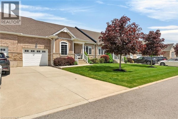 Exterior of a townhouse with brick and stone accents, featuring a garage door. - 38 Gamble Lane, Port Dover